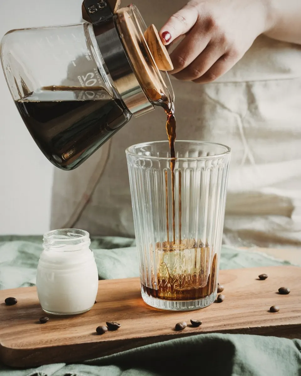 Coffee poured from a carafe over ice, with a jar of cream