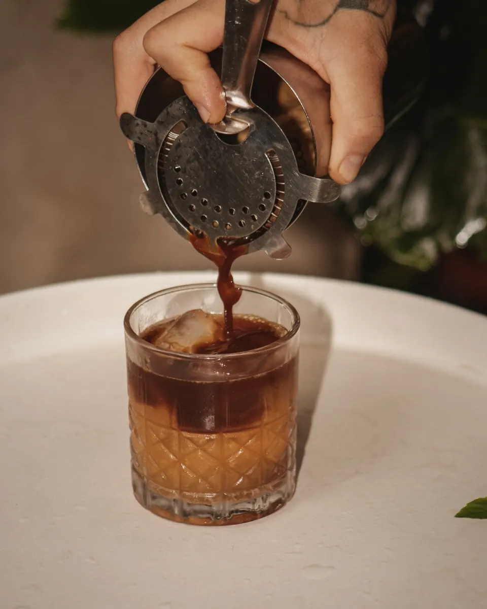 A coffee drink strained over a large cube